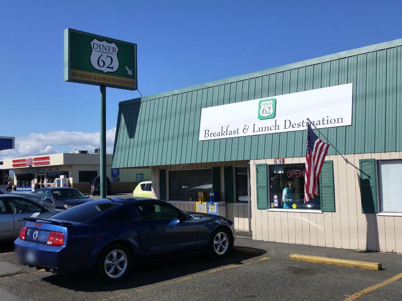 Diner 62 on Crater Lake Highway: green metal-sided building with a 'Breakfast & Lunch Destination' banner, an American flag and the tall green pole sign